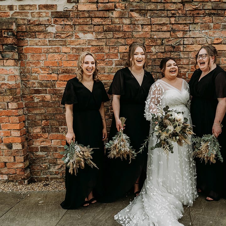 Bridal party in black bridesmaid dresses with the bride in long sleeve lace wedding dress