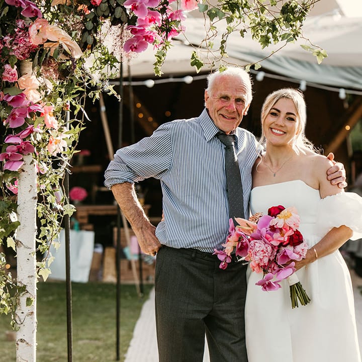 Bride and grandad pose together for special wedding photo with pink wedding flowers 