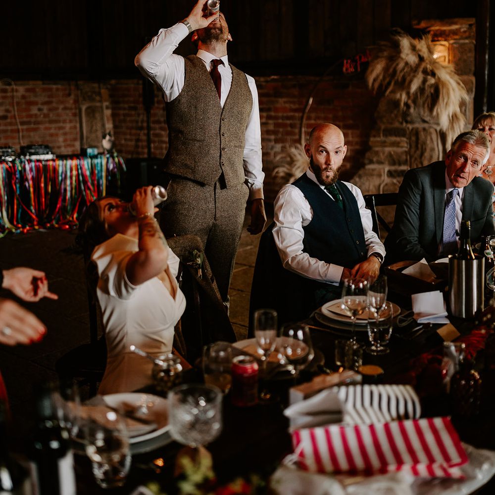 The bride and groom down their wedding drinks at their fun festival theme wedding 