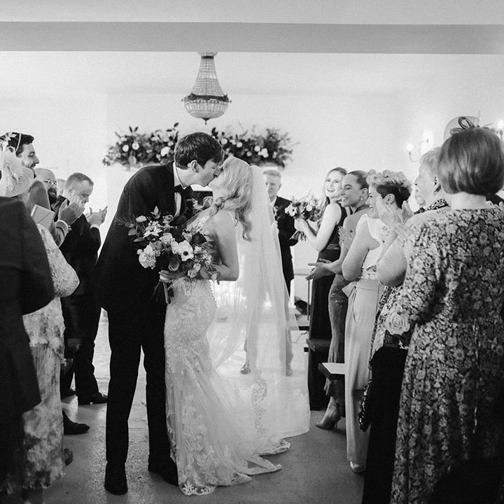 The bride and groom share a passionate kiss as they walk back down the aisle together 