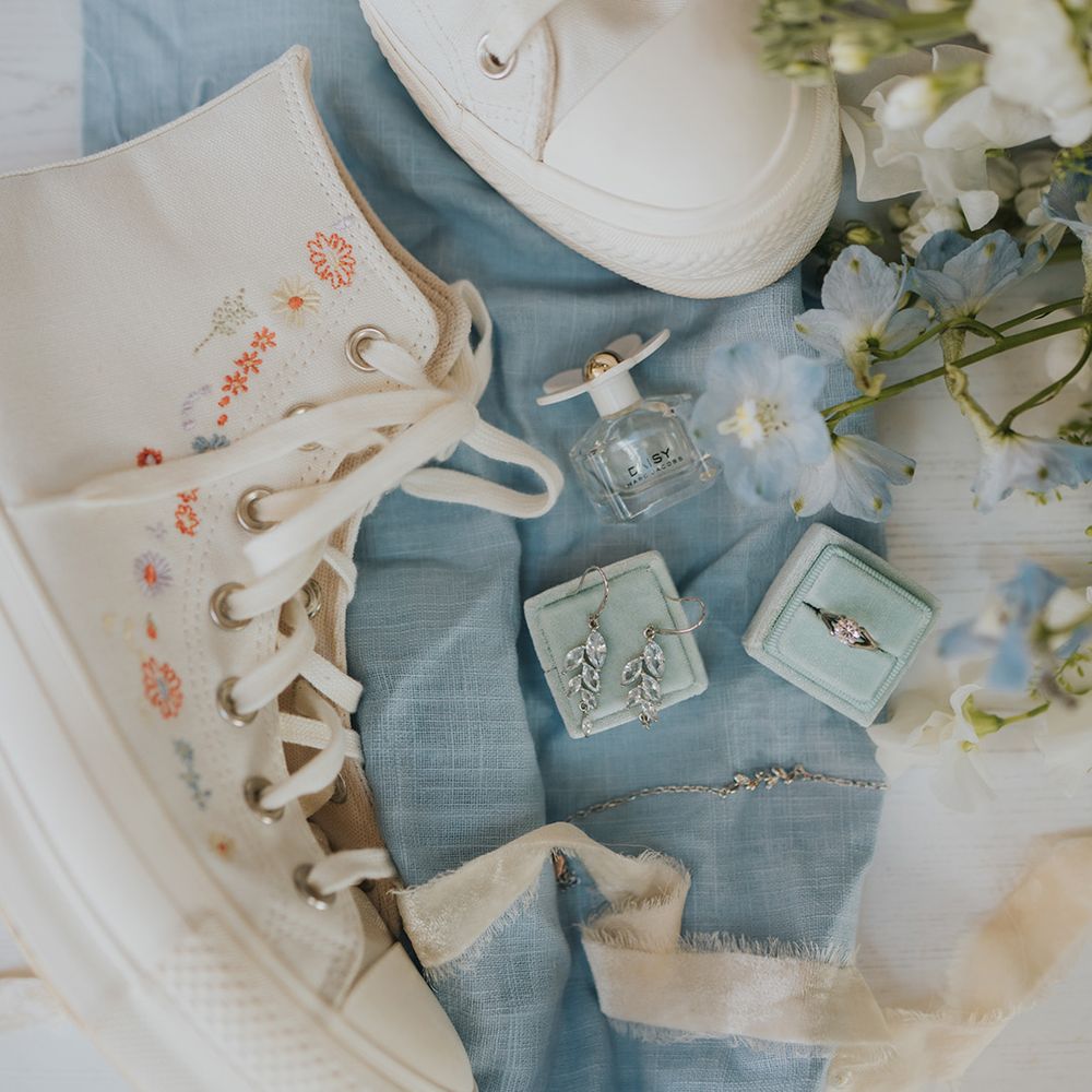 Blue ring box with blue floral bouquet with bridal perfume by Marc Jacobs and wedding flats Converse 