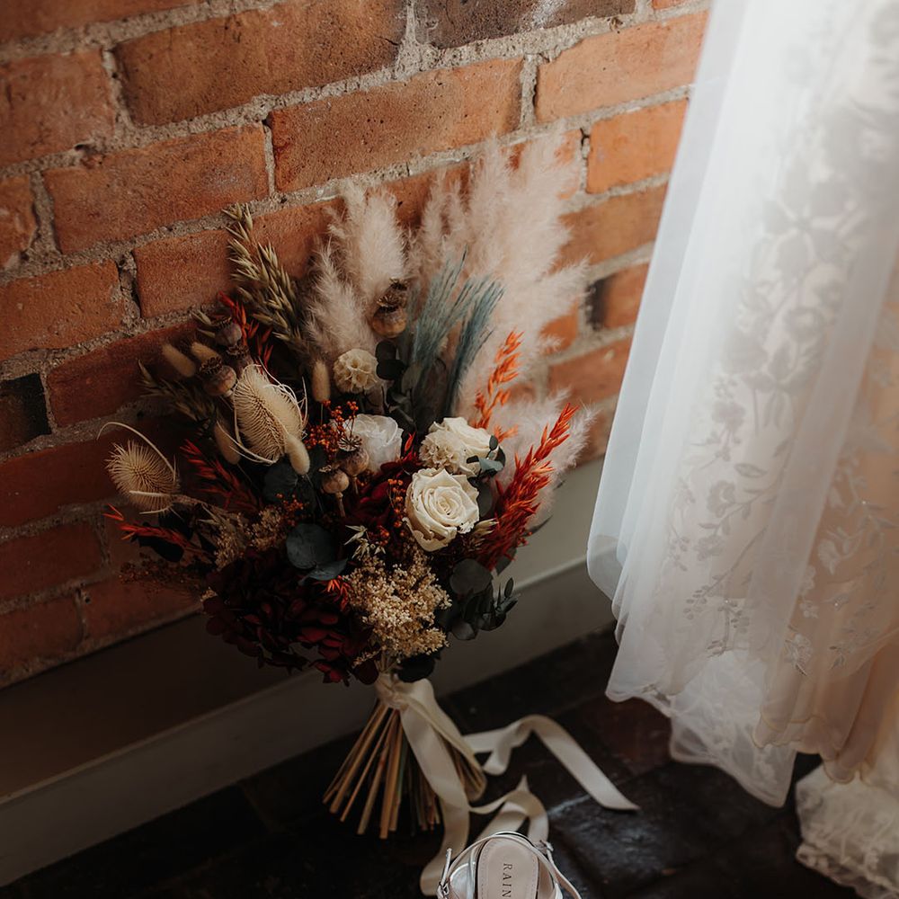 Dried wedding flower bouquet with bunny grass for autumnal wedding next to the pearl bridal shoes 