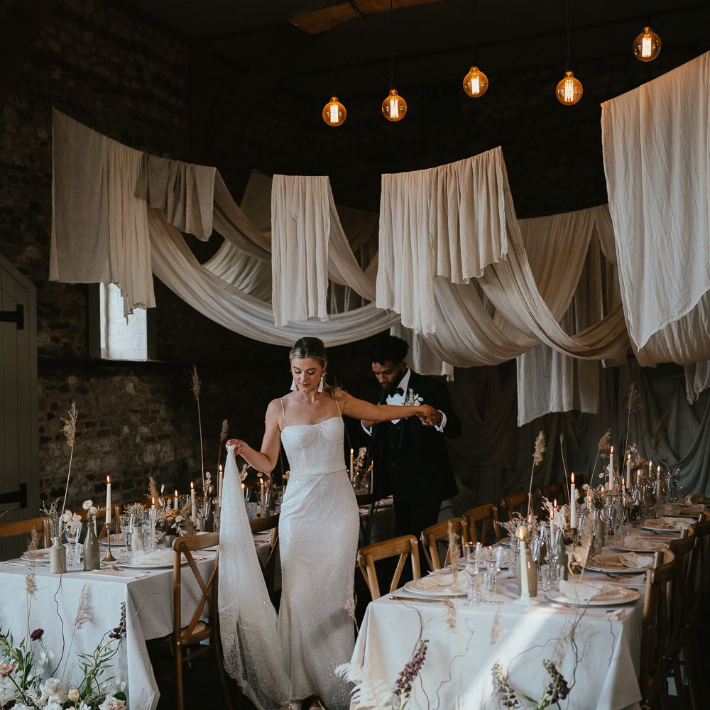 Modern luxury wedding reception with dried flowers, taper candles, drapes and ornate tableware 