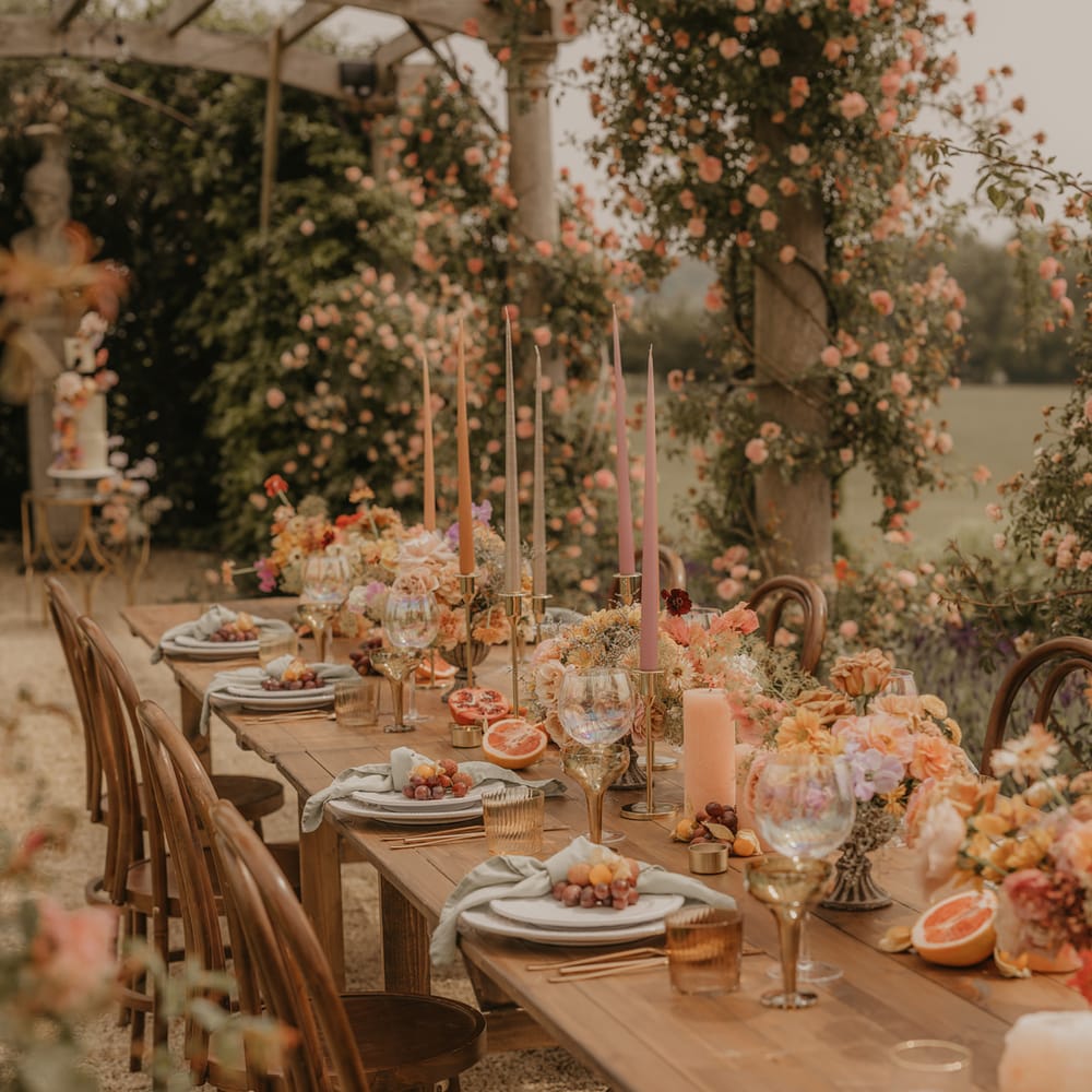 Zingy wedding table decor with orange candles, blush flowers and gold accents 