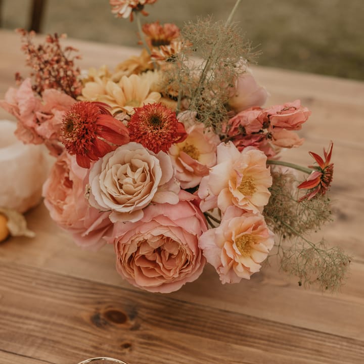 Wedding centrepiece with pastel orange, pink, coral and peach flowers 