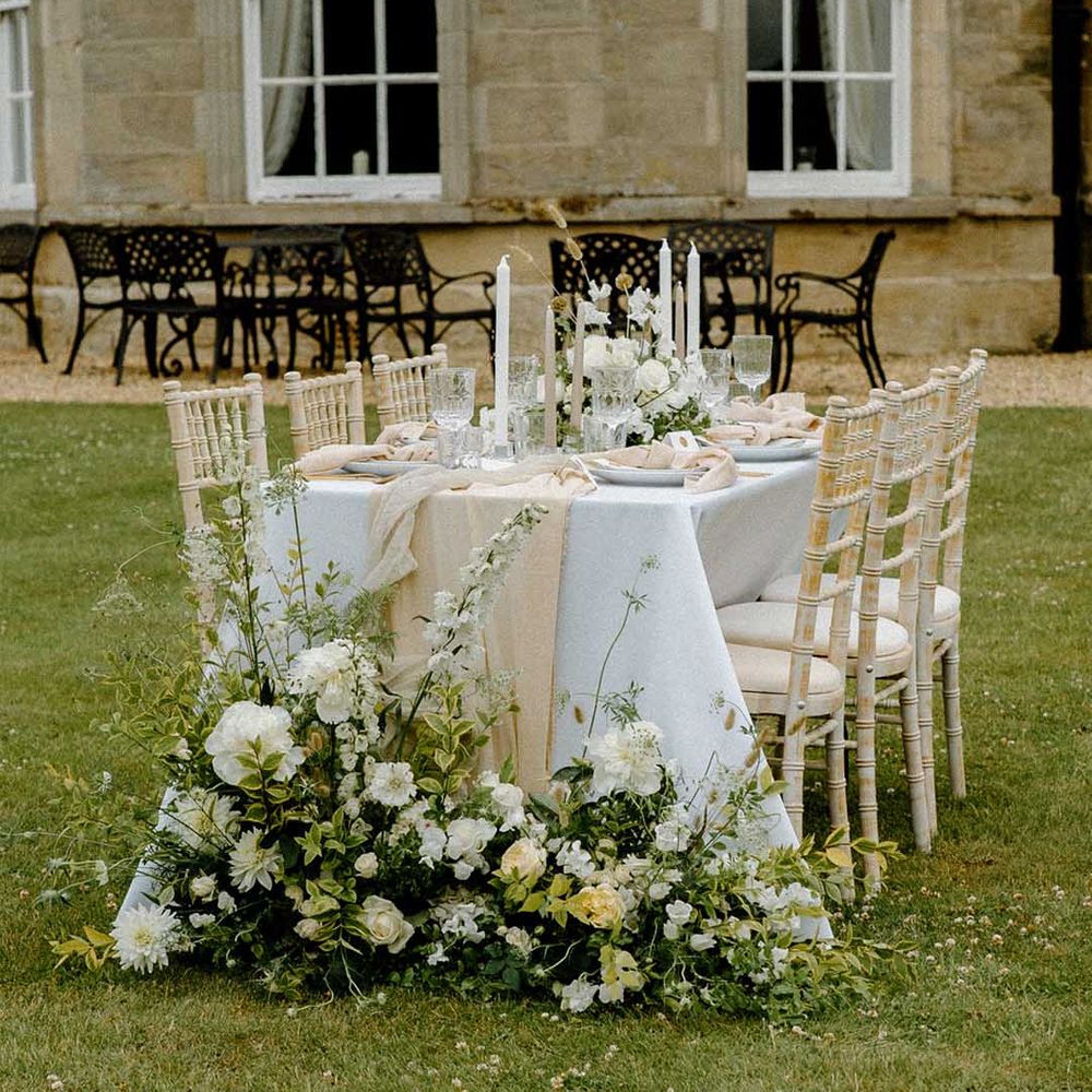 Intimate outdoor tablescape with white and green wedding flowers and taper candles 