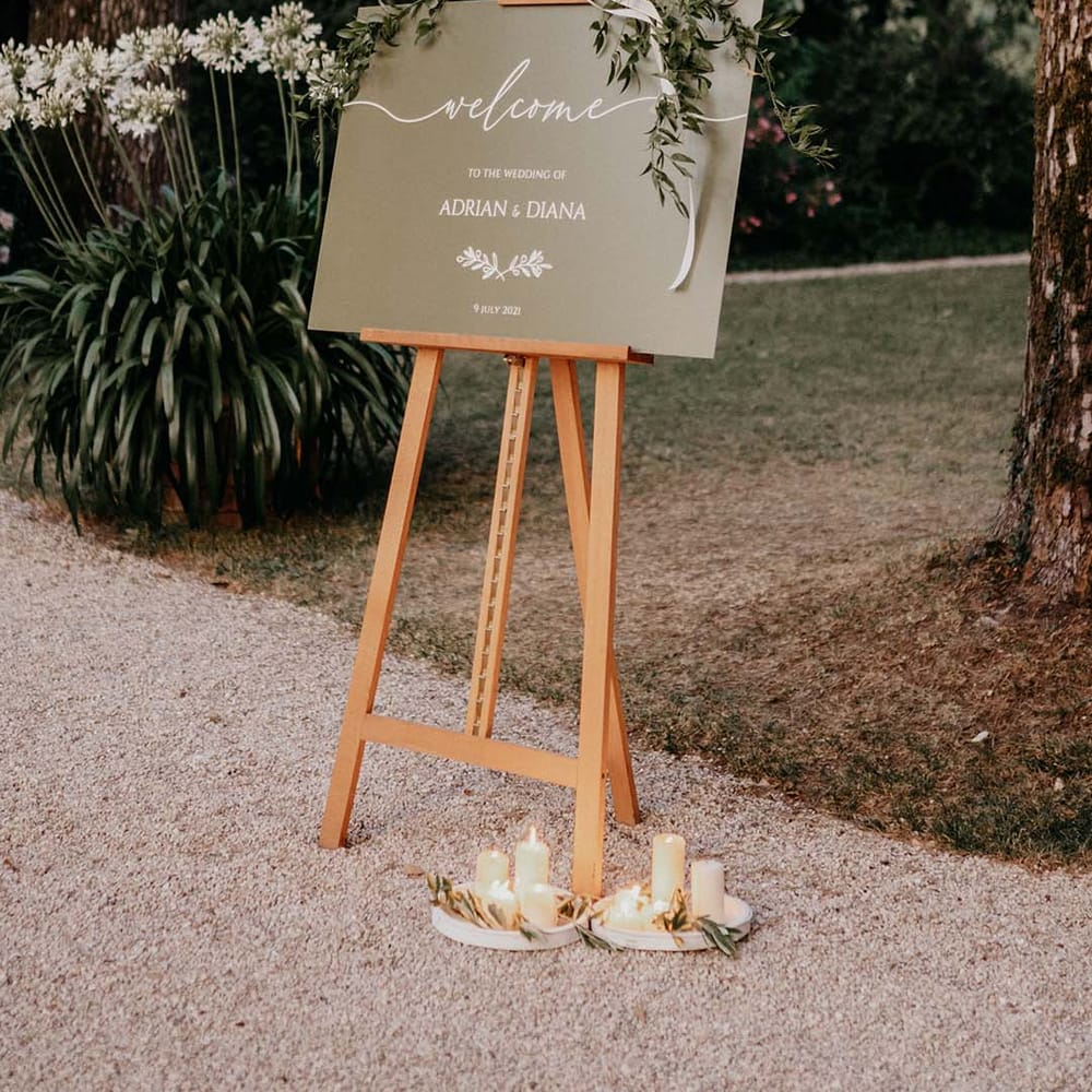 Wedding sign complete with white writing against green background set on wooden easel outdoors | Royal Studio