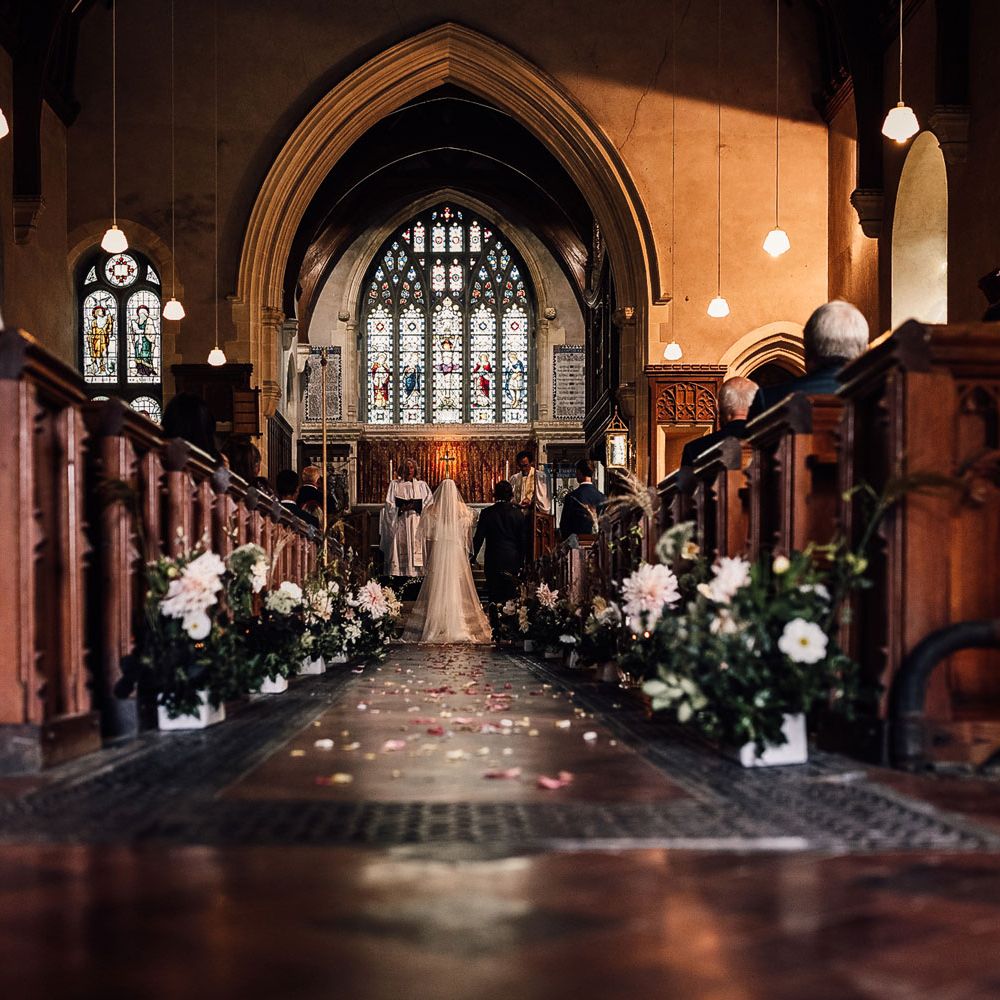 Bride in Halfpenny London Mayfair dress and groom in suit stand at the altar during church ceremony in Cornwall