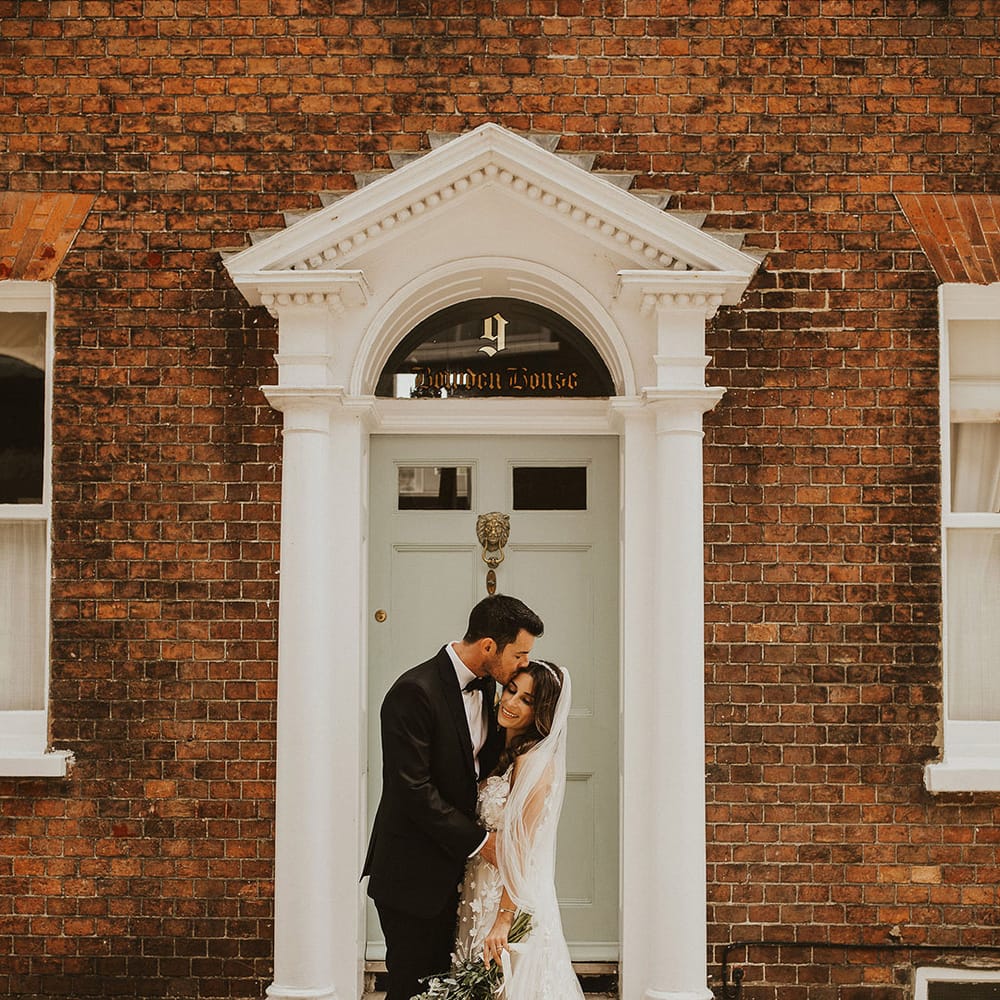 Bride & groom kiss in doorway on their wedding day