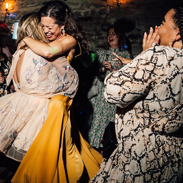 Bride hugs wedding guest during reception on dancefloor 