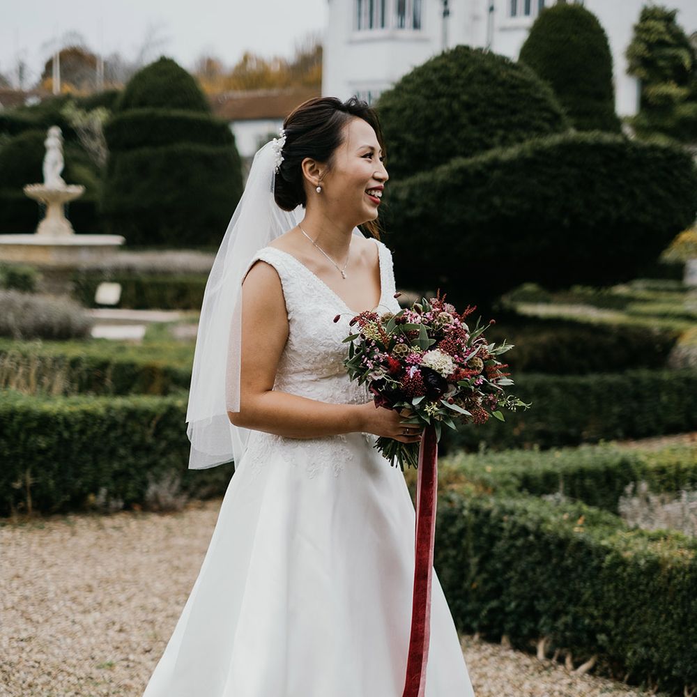 Bride with deep red lipstick smiles as she clutches bouquet