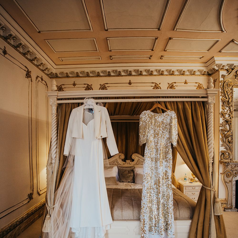 Suzanne Neville bridal gown beside Abigail Of Gardenia reception gown both hang above four poster bed 