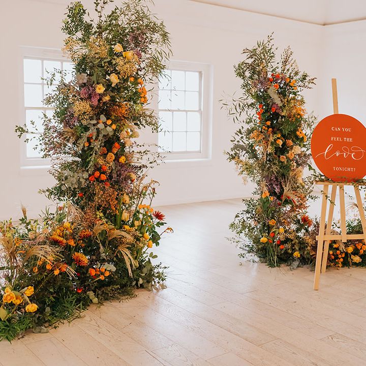 Minimalist wedding with golden wedding flowers and decor including column arrangements and orange sign on an easel