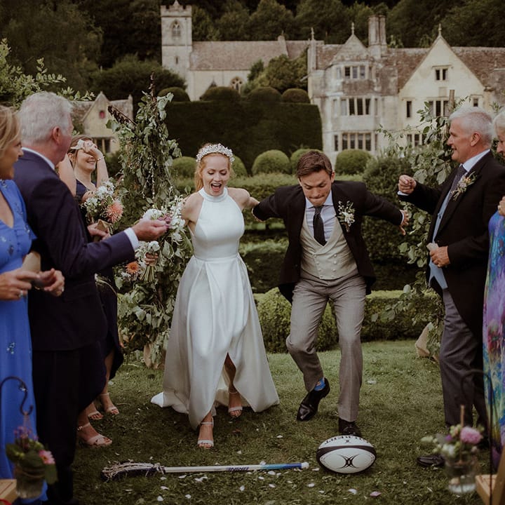 Bride and groom get ready to jump over a rugby ball and lacrosse stick 