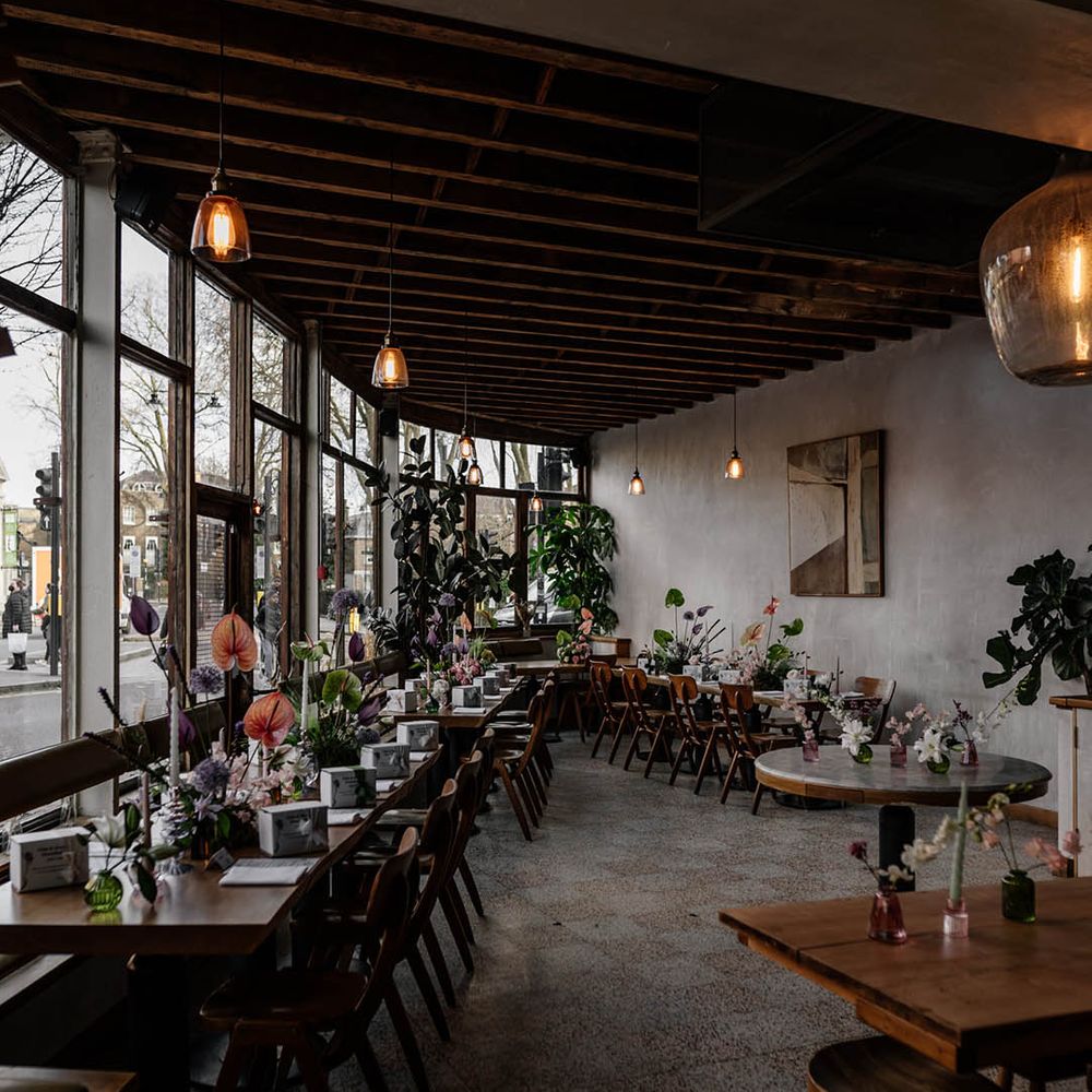 intimate wedding reception at Perilla with wooden tables decorated with pastel flowers stems including Anthuriums 