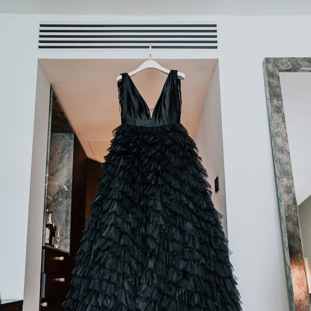 Black ruffled wedding dress hangs on the morning of wedding day