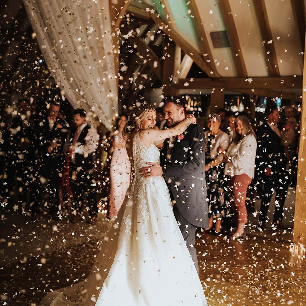 Bride and groom dance together as confetti explodes around them 