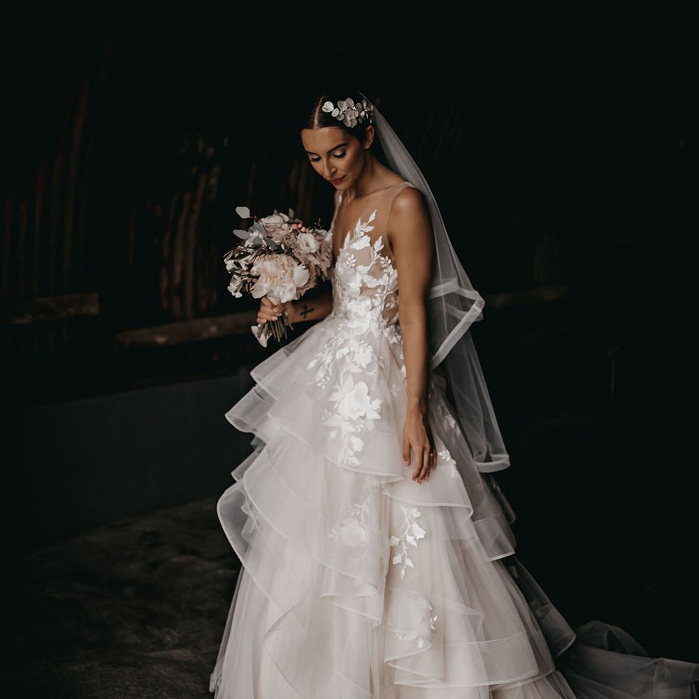 Bride wearing a floral lace tulle wedding dress with a flower hairpiece and soft pink bouquet 