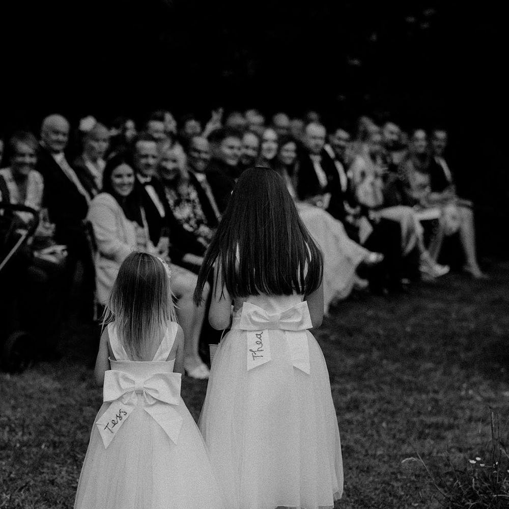 Flower girls in tulle dresses with large bows on the back personalised with their names 