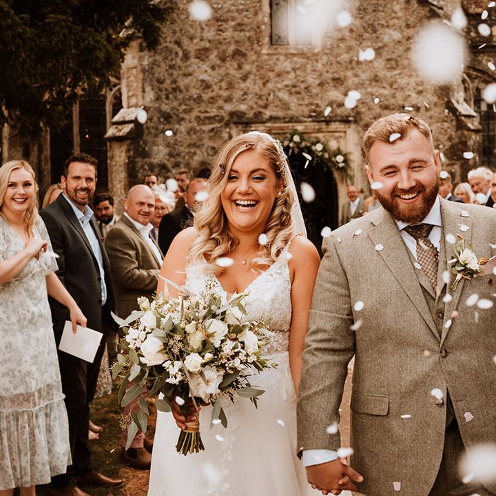 The happy couple exit their ceremony to white confetti 