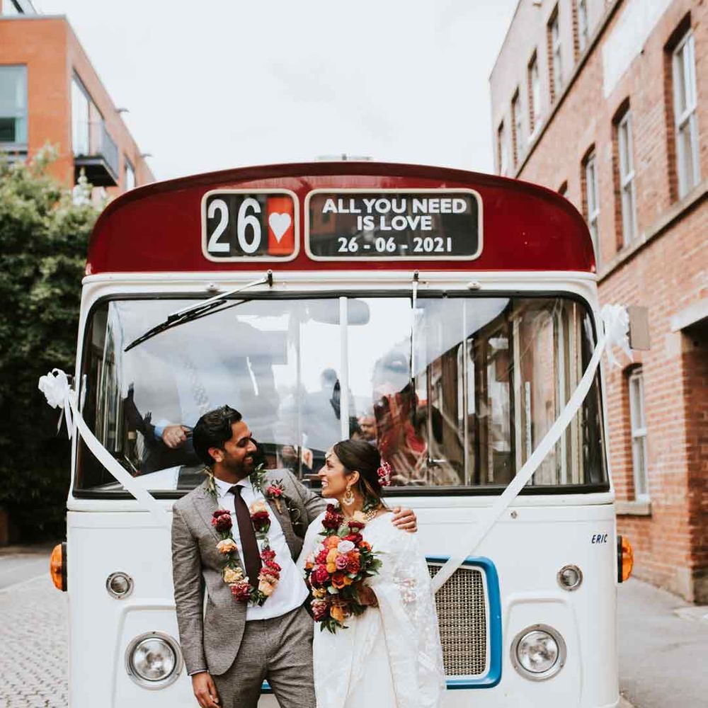 Large white and red wedding bus at Indian British wedding in Sheffield with white ribbon decor