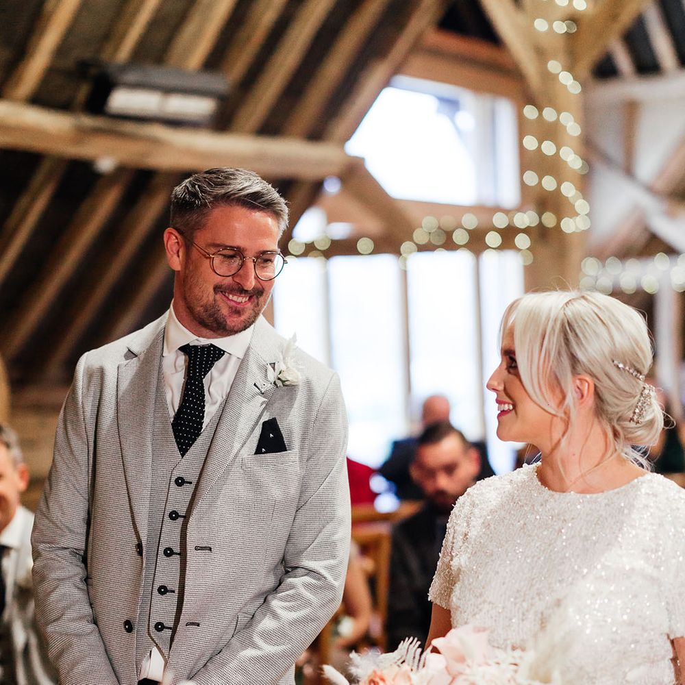 Light grey suit jacket and waistcoat with polka dotted tie smiling with the bride wearing a sparkly and tulle bridal separates 