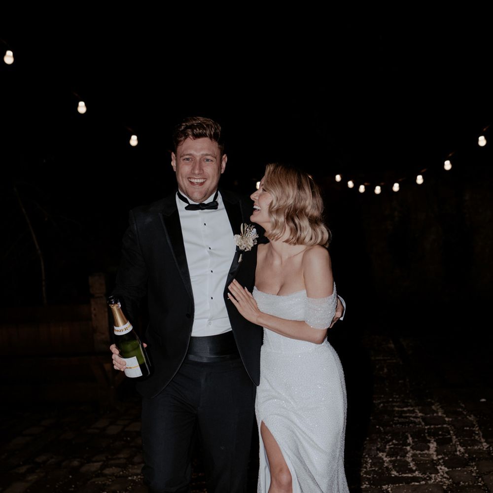 Lancashire wedding with the bride and groom walking together with a bottle of champagne to celebrate their wedding day 