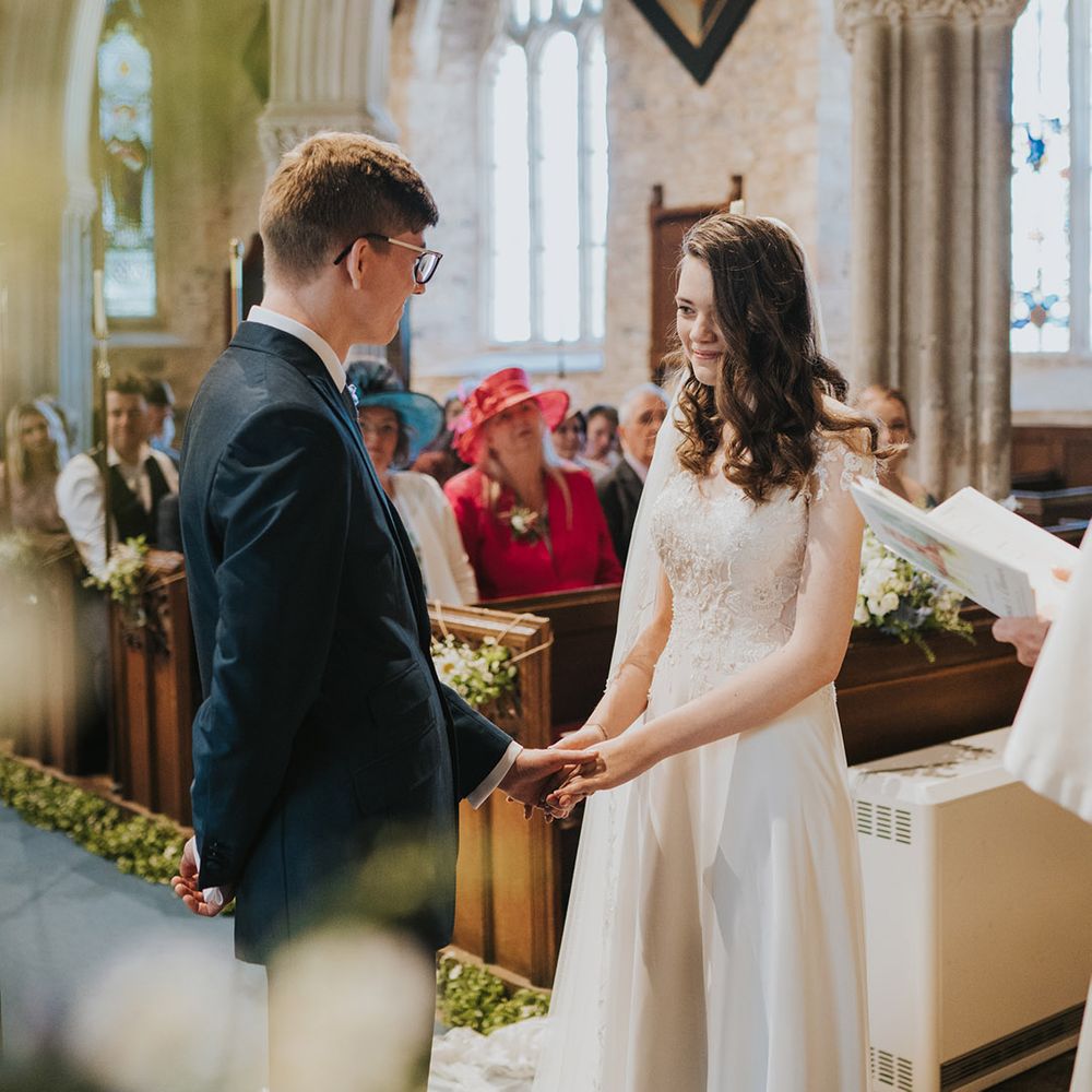 Groom in navy wedding suit with glasses facing the bride for the wedding day at their religious church wedding 