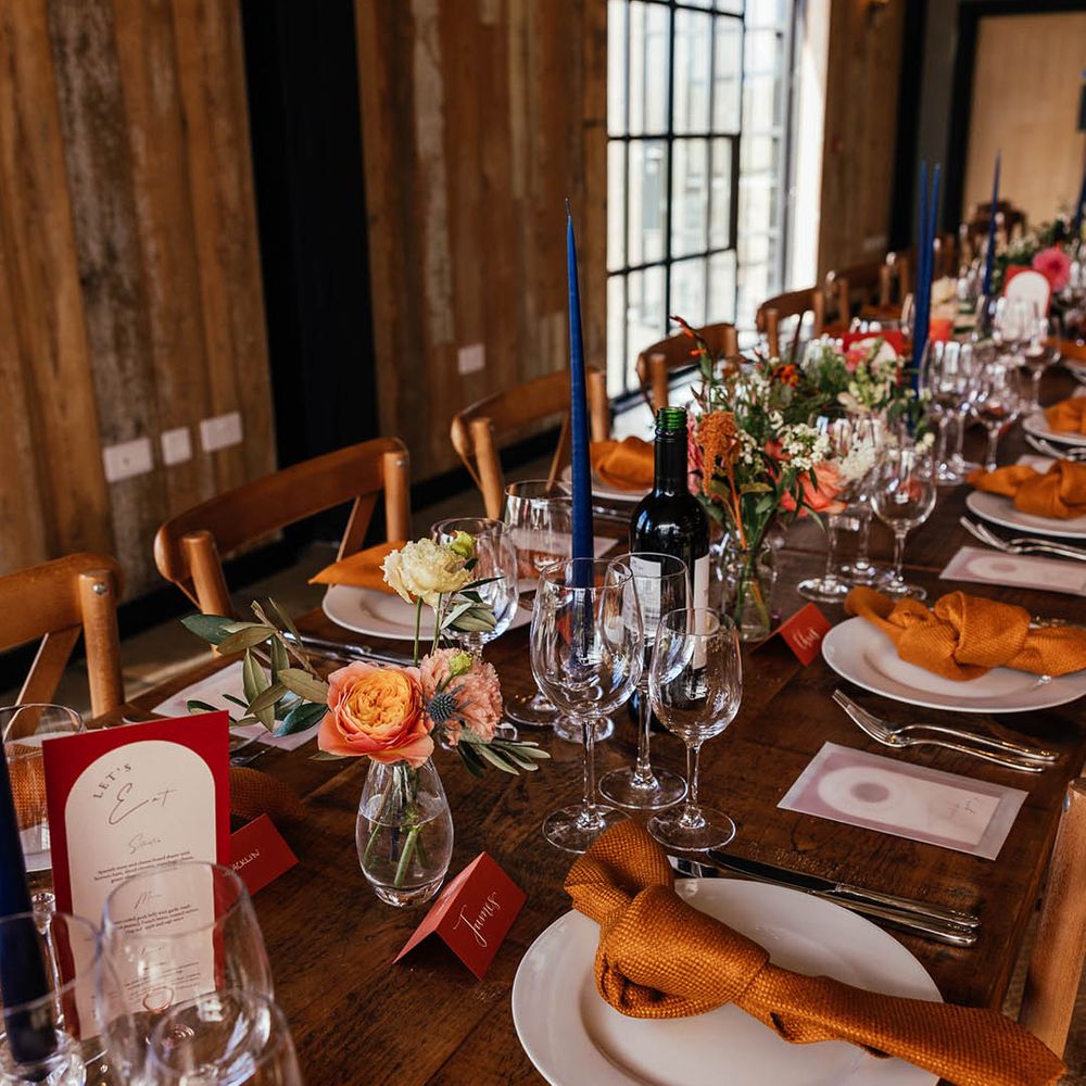 Tall blue taper candle with orange and copper theme wedding place setting for autumnal barn wedding 