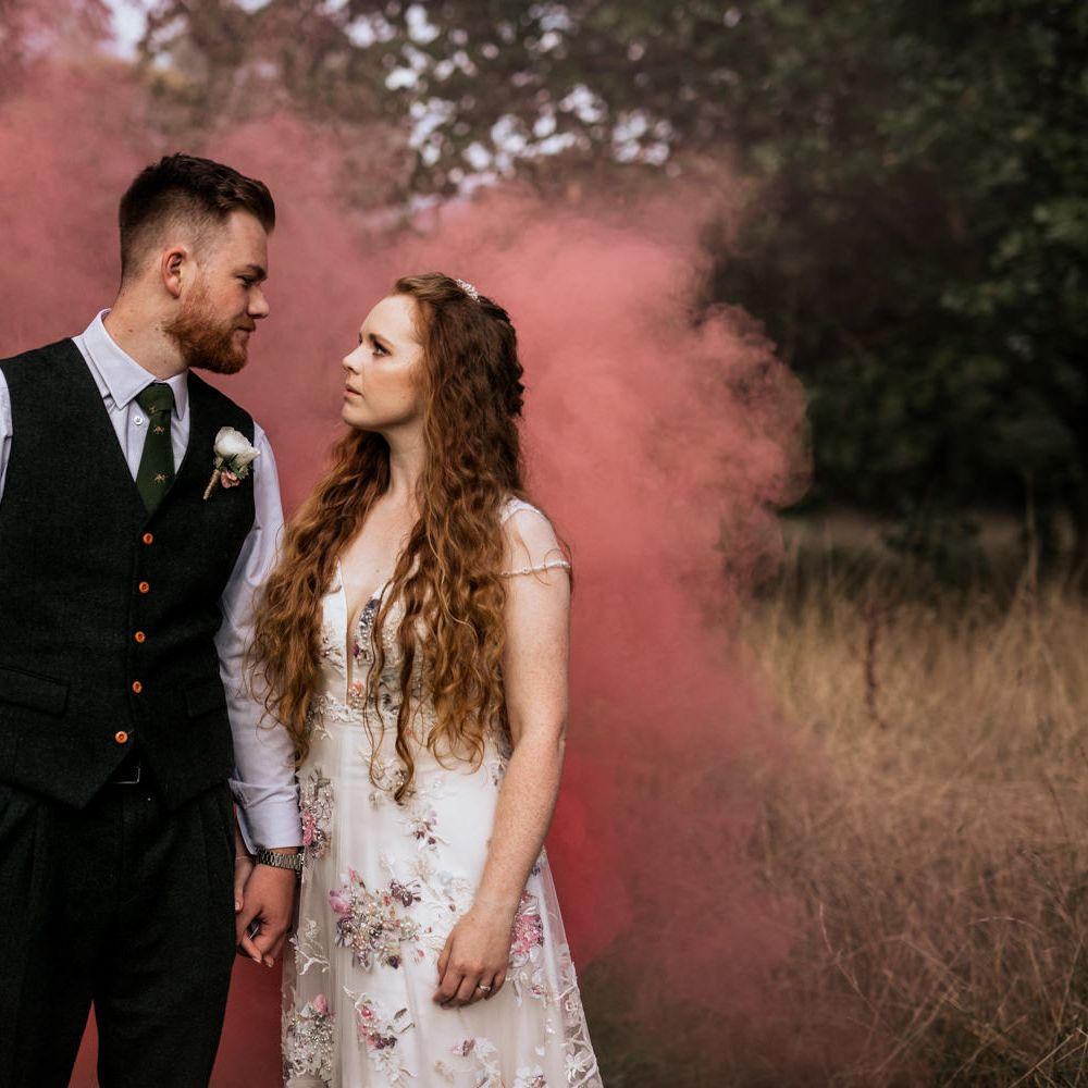 Bride & groom pose in front of pink smoke bomb