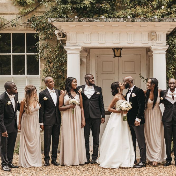 Wedding party portrait outside Northbrook Park with the bride in a Oleg Cassini wedding dress, Bridesmaids wearing dusky pink dresses and groomsmen in tuxedos and bow ties. 