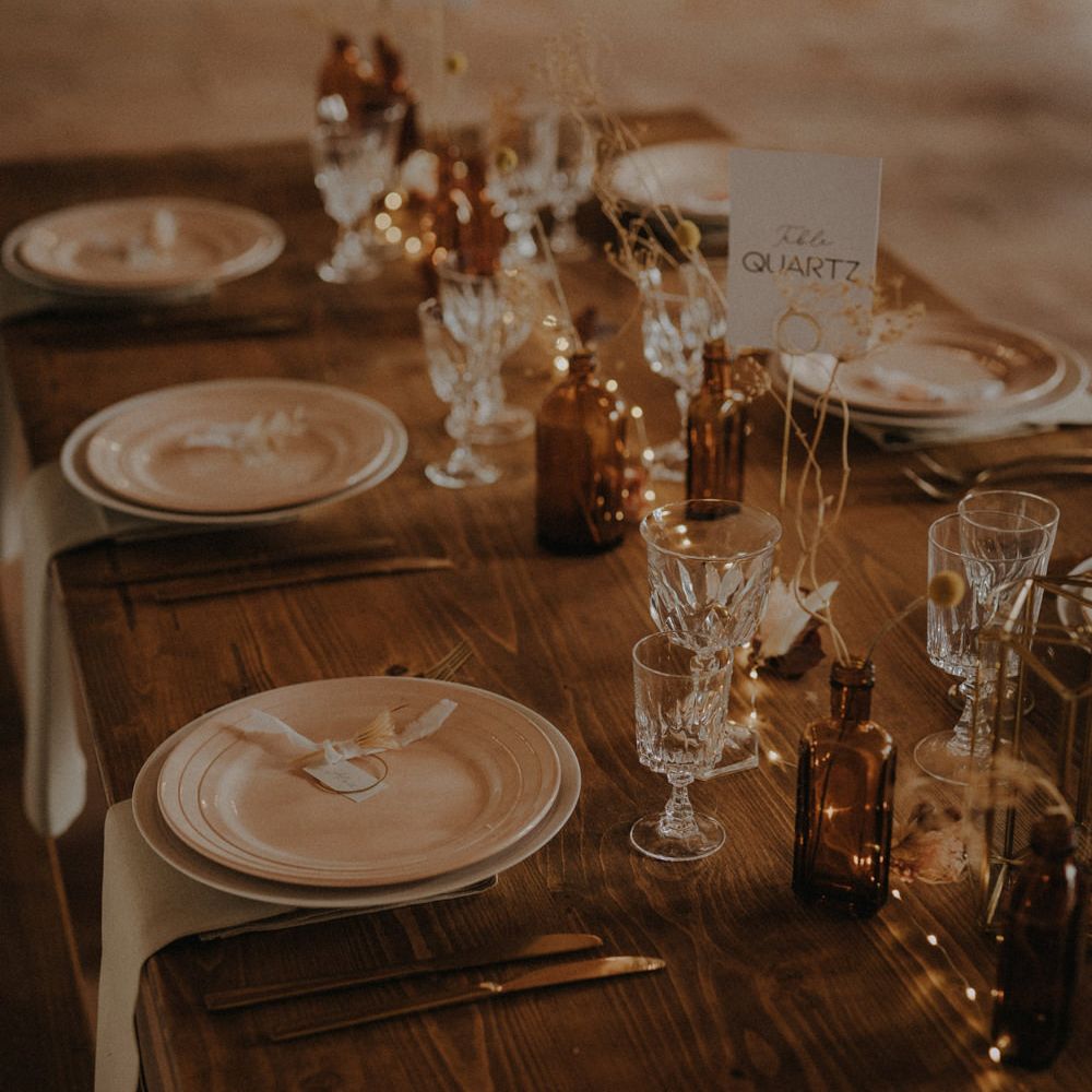Minimalist table setting decor with dried grasses, coloured glassware and wooden table 