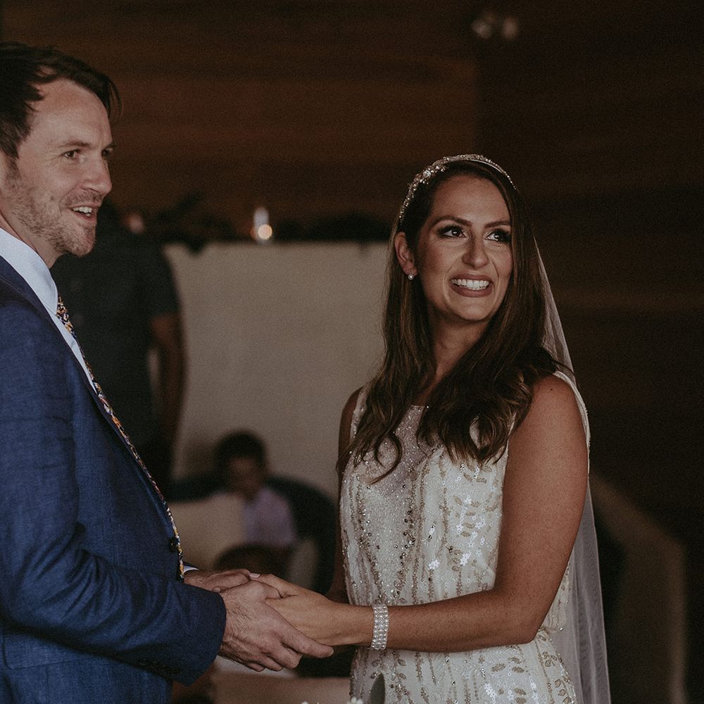 Bride & groom stand together and hold hands on their wedding day during ceremony