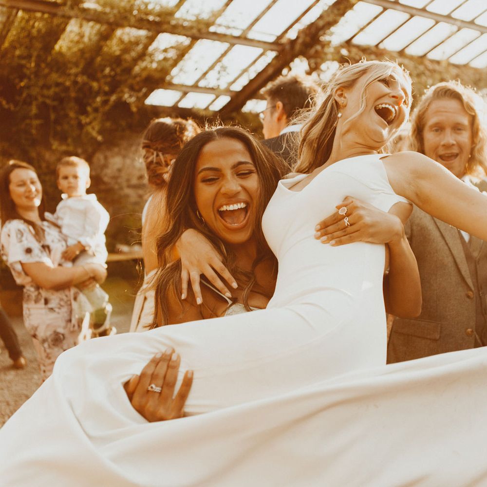 Bride in white Made With Love wedding dress is swung around by guest during golden hour at the glasshouse at Anran Devon
