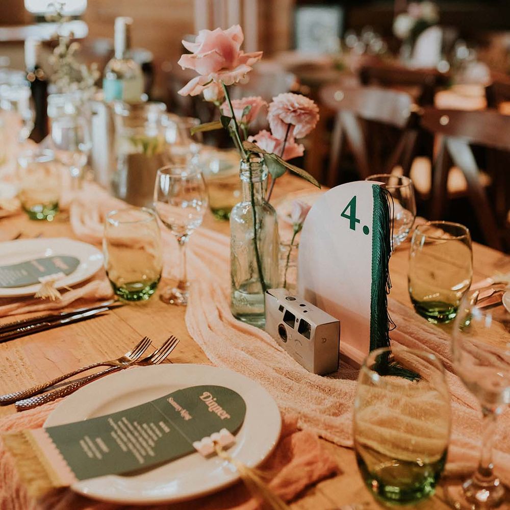 Wedding tablescape complete with disposable camera and retro vibe with neutral toned table runner through middle of table
