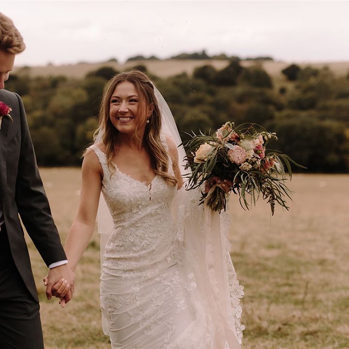 Bride in Pronovias wedding dress holds hands with Groom as she walks through White Pond Farm venue