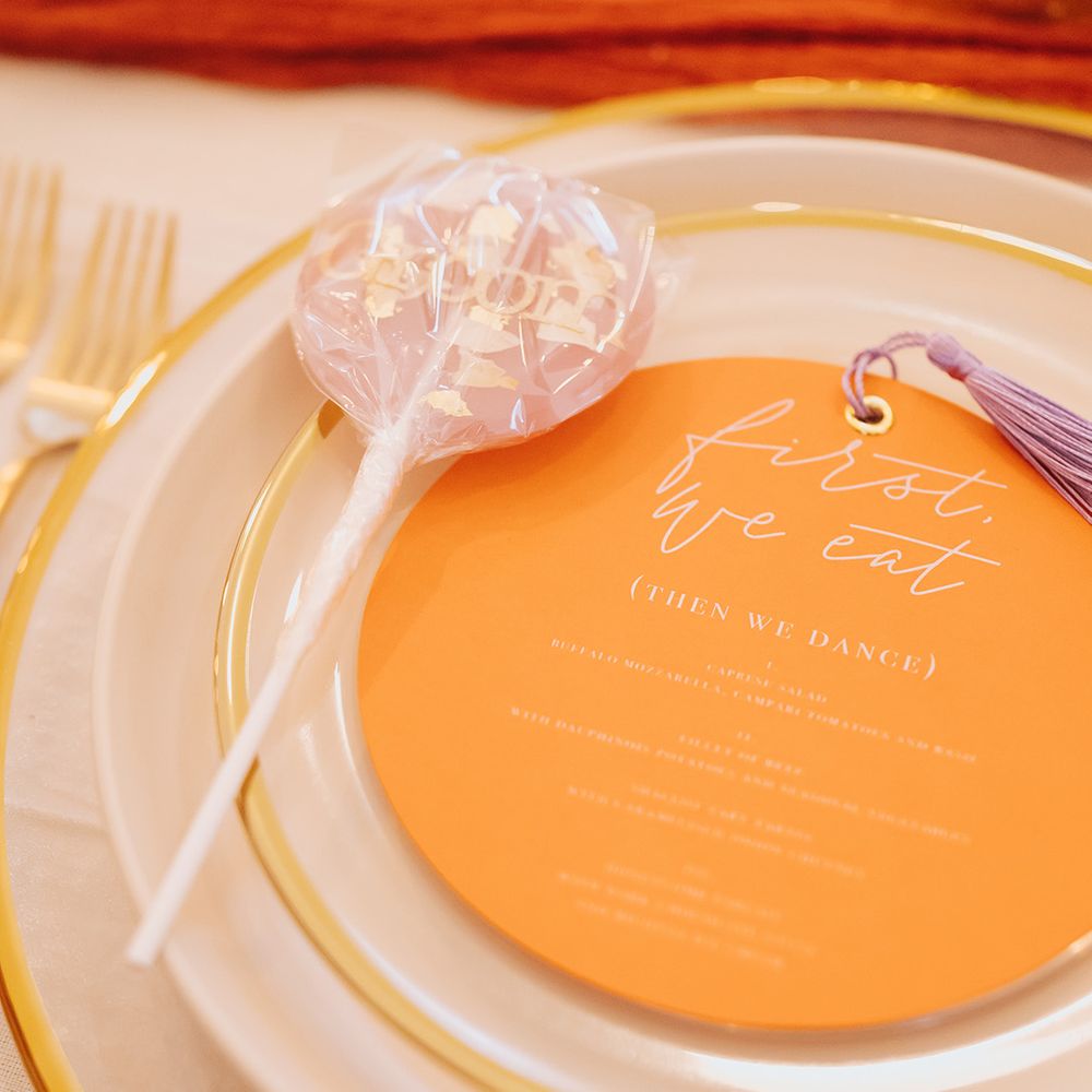 Groom lollipop wedding favour on place setting with orange menu card