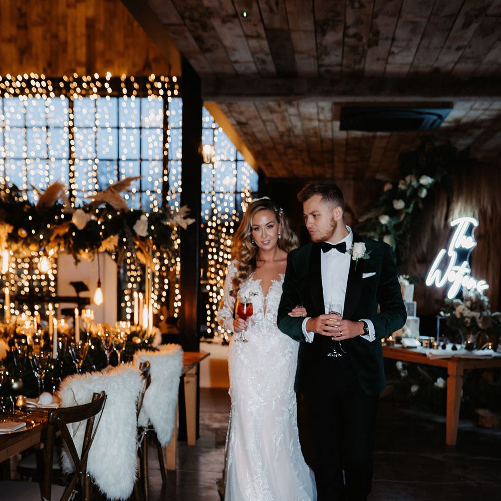 Bride and groom in black tie walk around their wedding reception at Hidden River Barn