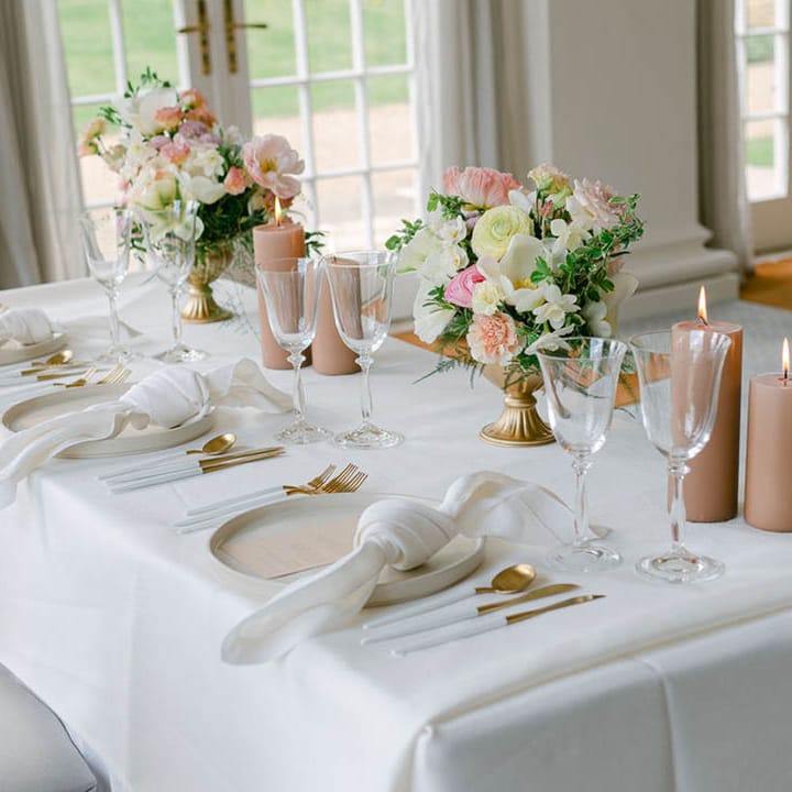 Intimate sweetheart table with neutral and beige colour palette including pillar candles and gold cutlery 