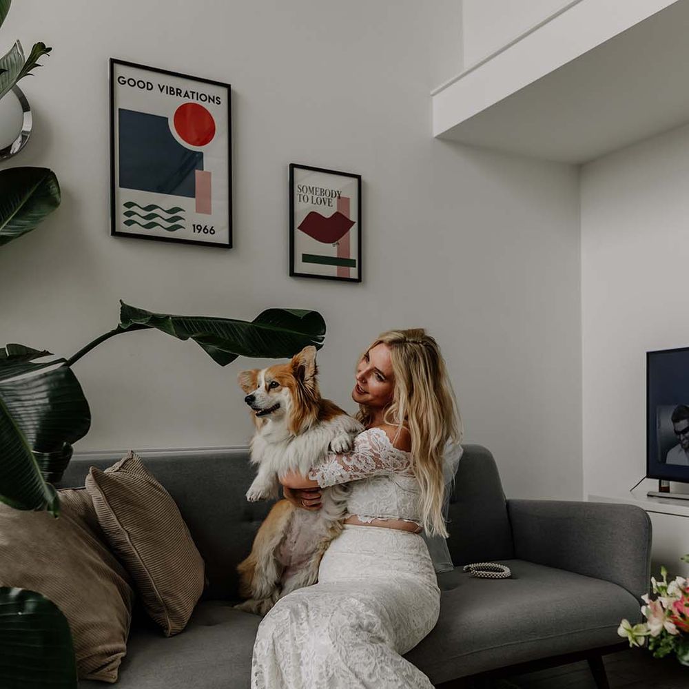Bride in lace boho two piece holding corgi puppy getting ready for stylish wedding