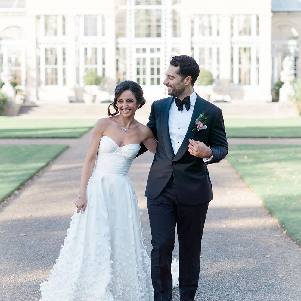 Bride in bespoke Emma Beaumont wedding dress walks alongside her groom in black tie 