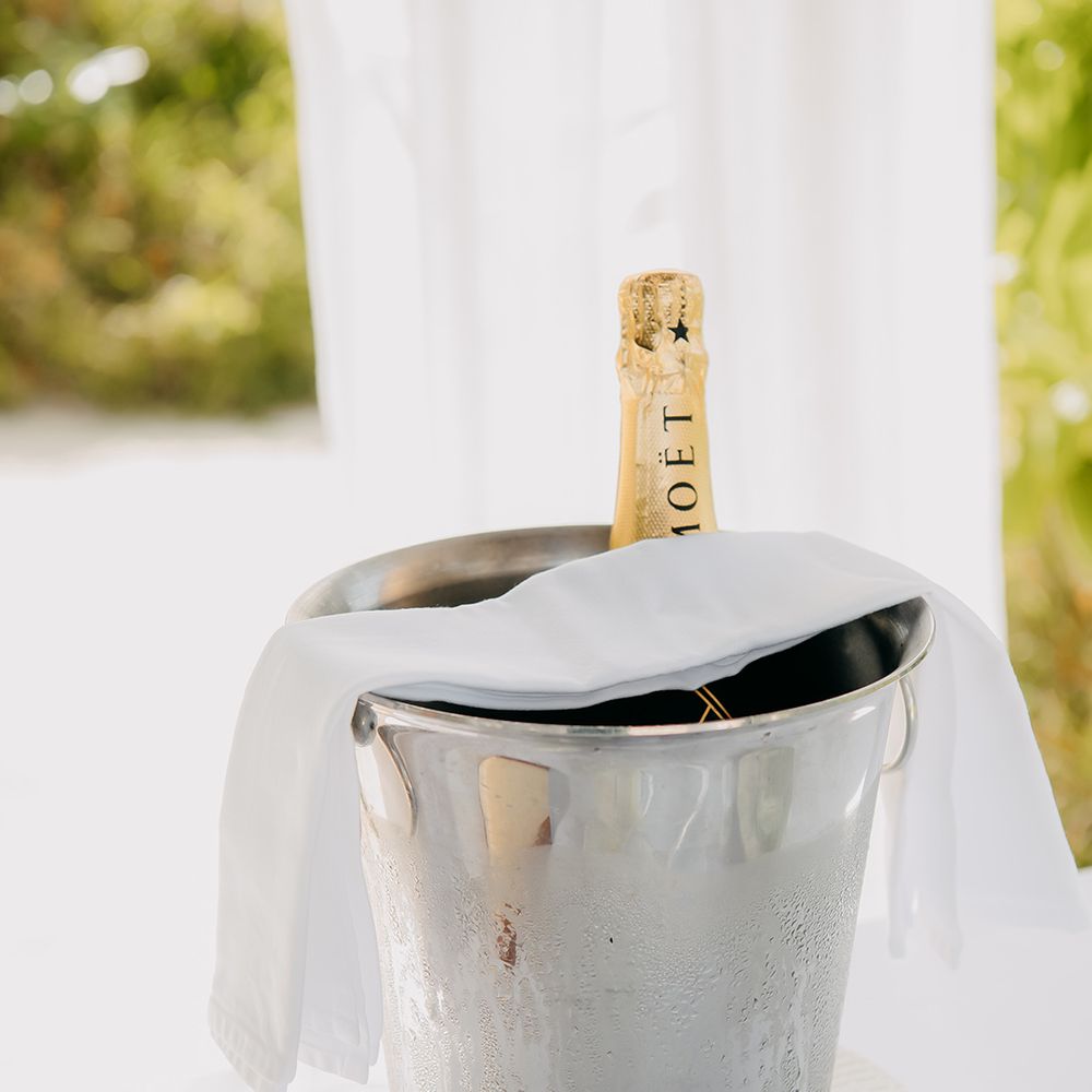 Silver champagne bucket with white cloth and bottle of Moet champagne inside