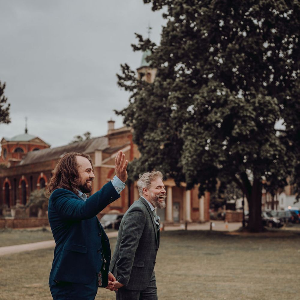 Grooms walk outdoors across the ground of Kew Gardens for LGBTQIA+ wedding 