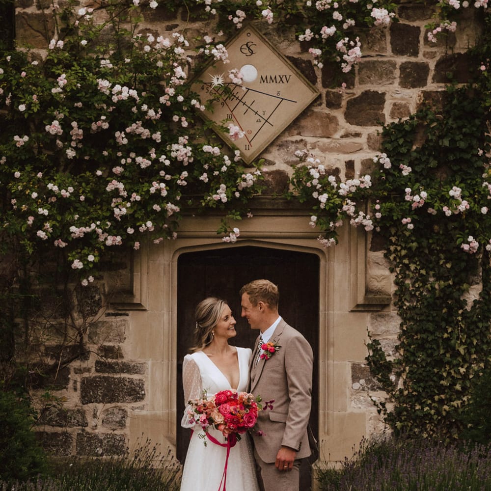 The bride wearing a plunging wedding dress with long sheer polka dot sleeves from Sassi Holford with the groom in a beige suit at The Courtyard in Shropshire