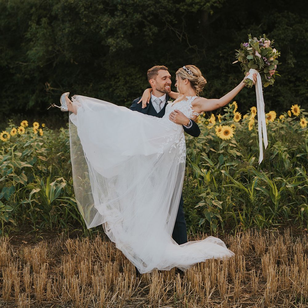 Dove Barn Weddings with the groom lifting the bride so she doesn't ruin her silver sparkly Jimmy Choo wedding shoes 