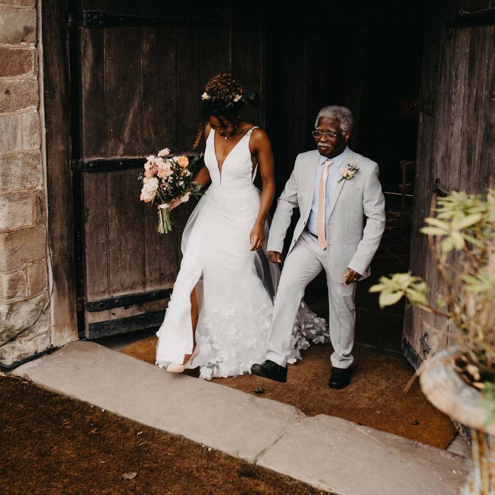 Bride in v neck sleeveless wedding dress with 3D floral applique train walking with father of the bride at Brinsop Court wedding