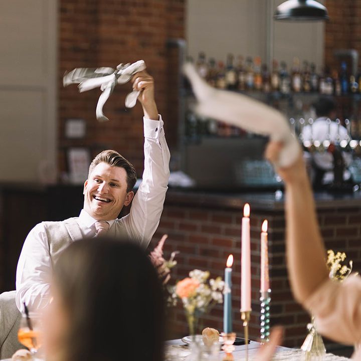 Wedding guest smiles brightly as he twirls the wedding napkin to greet the bride and groom 
