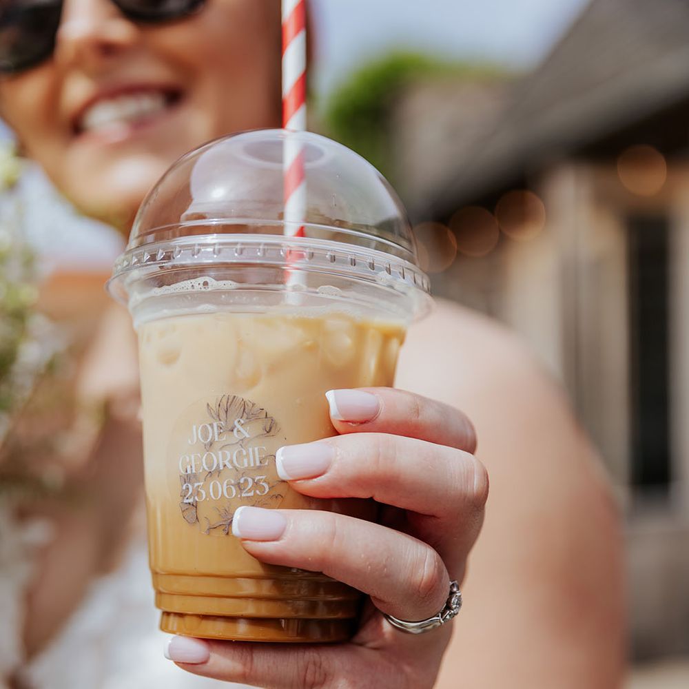 Bride drinking iced coffee in plastic cup with paper straw from the coffee van 