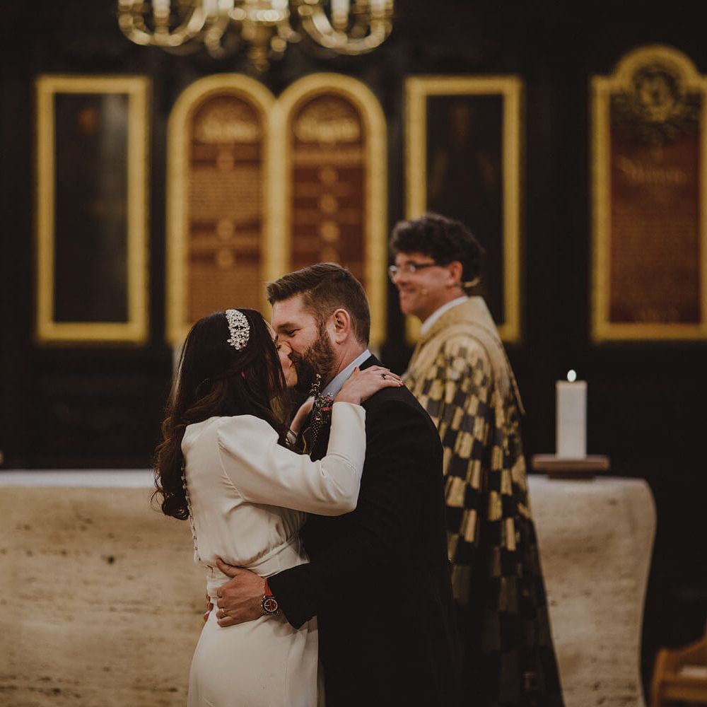 Bride and groom holding each other kissing at London wedding ceremony