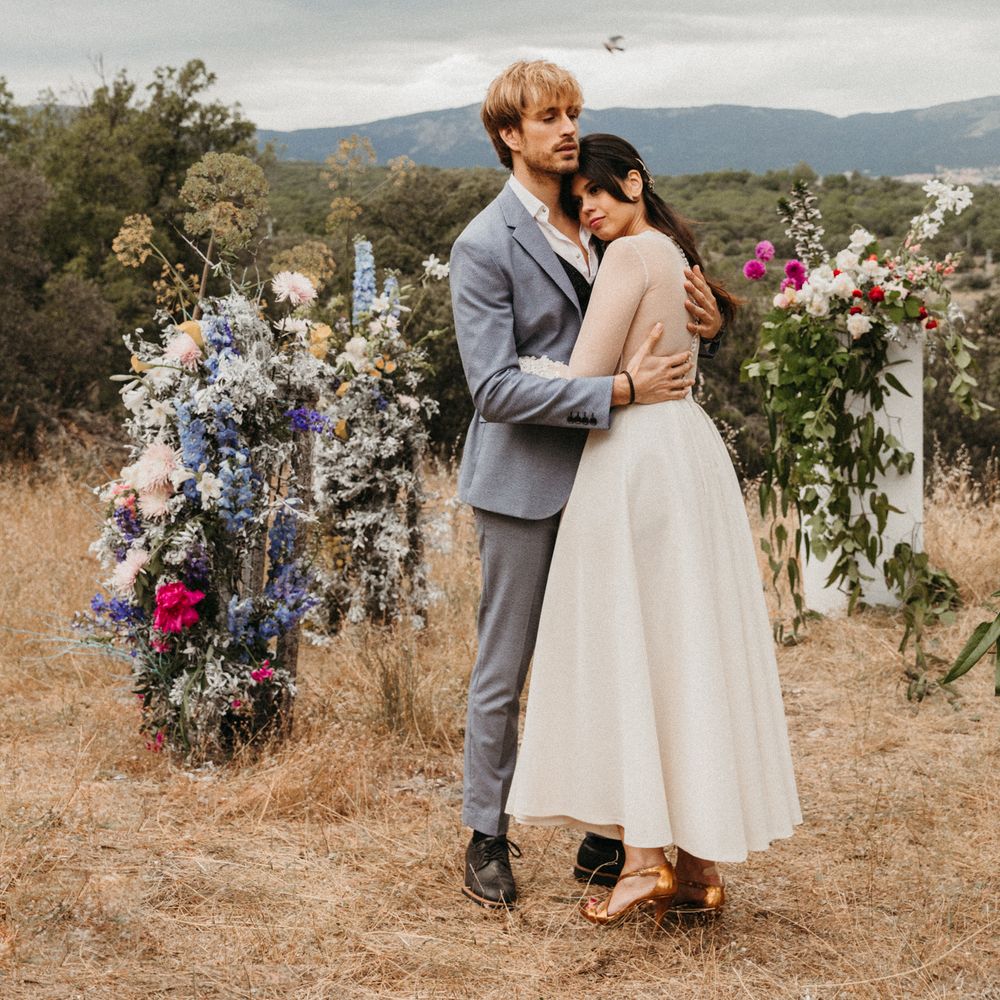 Bride & groom stand together with mountain backdrop and floral pillars